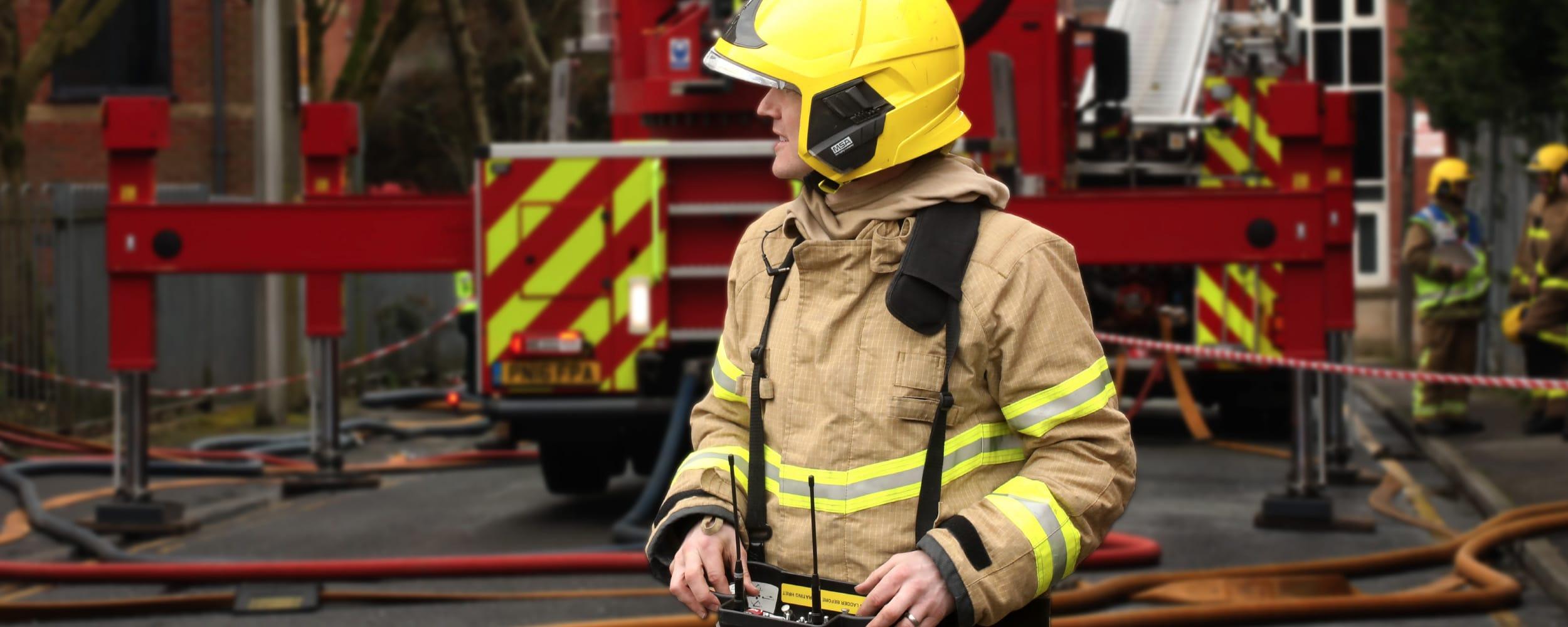 Image of firefighter in fire kit in front of an appliance looking into the distance